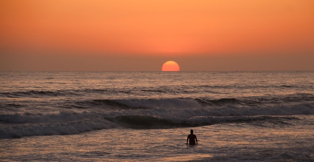 The whole pacific ocean to himself lone surfer at sunset