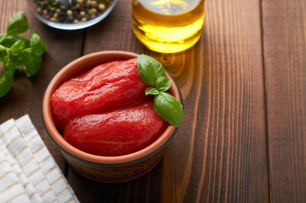 Pomodori pelati interi in una ciotola basilico aglio olio d'oliva copia spazio