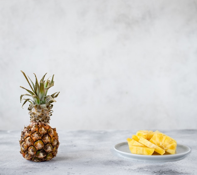 Whole pineapple fruit and sliced pineapple. light gray background