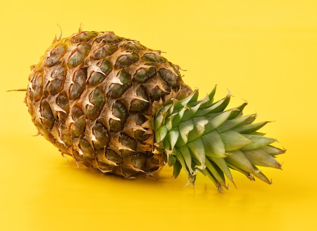 Whole pineapple on yellow wall.