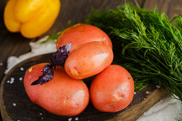 whole potato tubers, spices and coarse salt, rustic style, greens, cherry tomato branch, on a