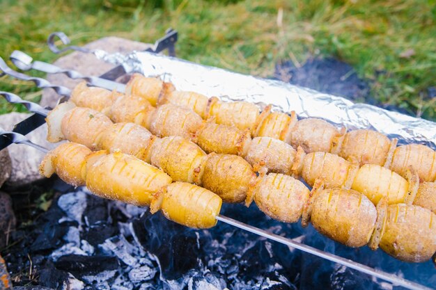 串に刺した素朴な方法で丸ごとポテト屋外バーベキューやピクニックで夏のパーティーのためのおいしいスナック自家製食品菜食主義