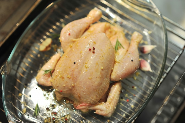 Whole raw chicken in a glass dish on the grill in the oven