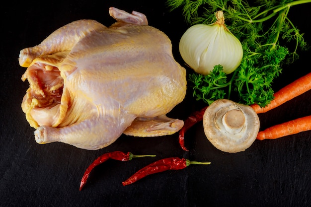 Целая сырая курица в маринаде и готовая к приготовлению с ингредиентами для приготовления.