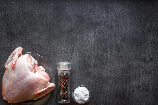 Whole raw chicken with spices on a wooden table