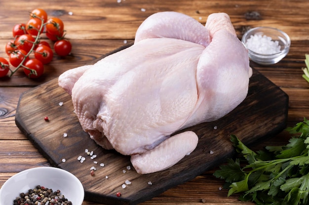 Whole raw chicken on a wooden board.