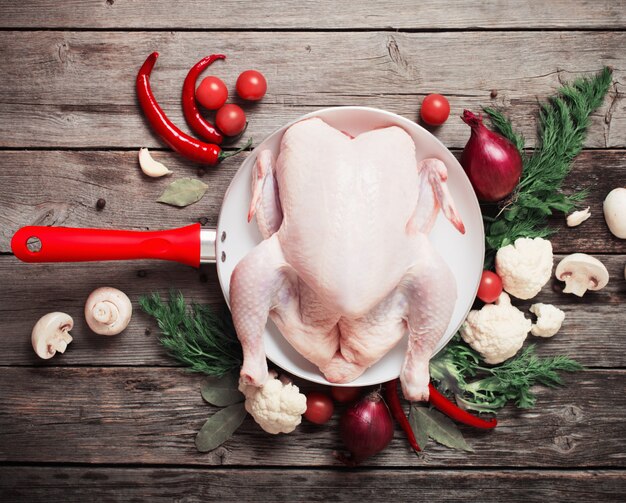 Whole raw chicken on a wooden table