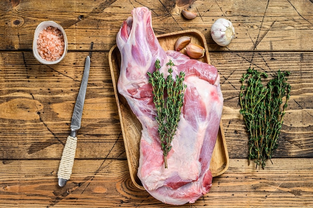 Carne intera di coscia di capra cruda su un vassoio di legno