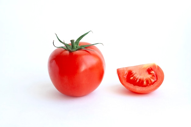 A whole red tomato and slice isolated on a white background