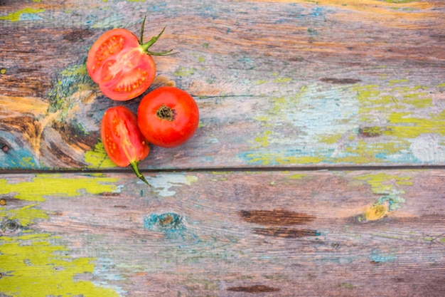 Whole red tomato with tomato slice on wooden surface