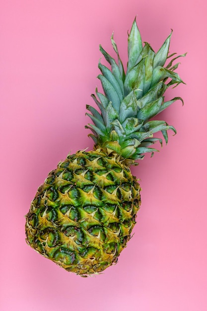 Whole ripe pineapple on the pink background