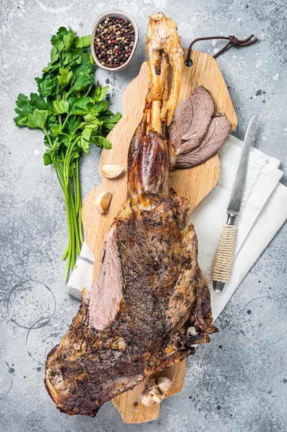 Whole roast mutton lamb leg with spices on a wooden board Gray background Top view