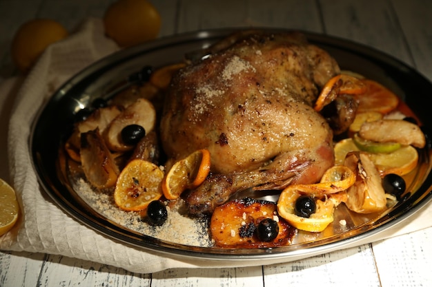 Whole roasted chicken with vegetables on tray on wooden background