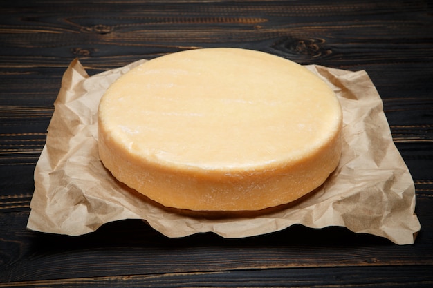 Whole round Head of parmesan hard cheese on wooden table