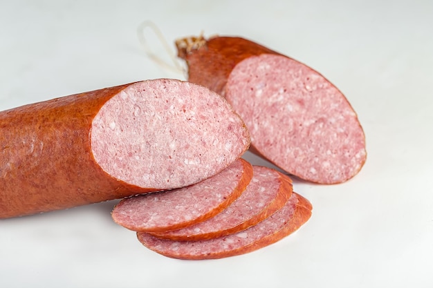 whole salami cervelat sausage lie on a vintage kitchen board on a white isolated background