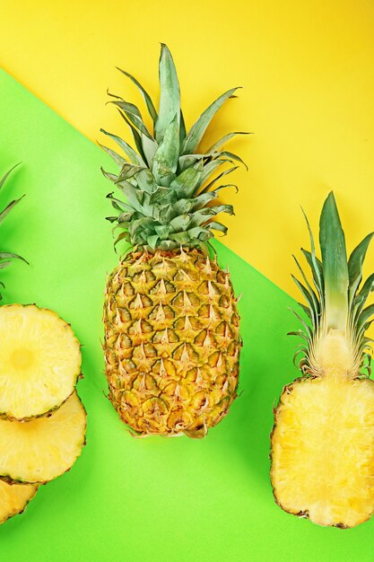 Ananas fresco intero e affettato su sfondo colorato