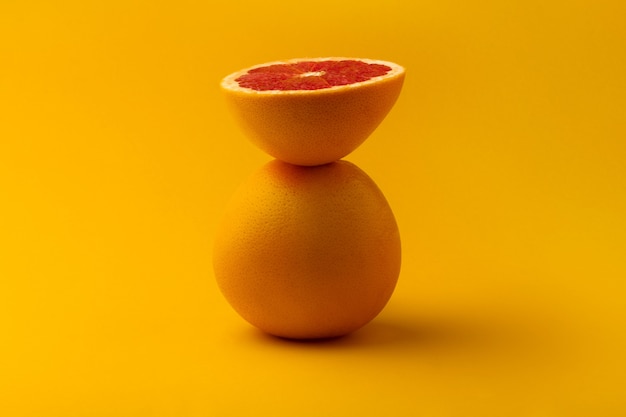 Whole and sliced grapefruit over yellow background