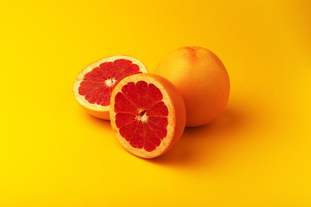 Photo whole and sliced grapefruit over yellow background