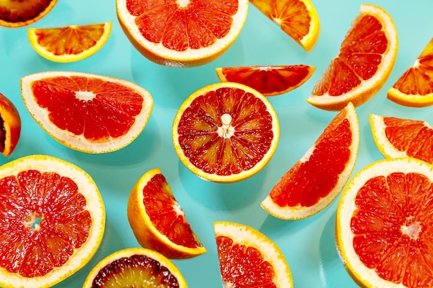 Whole and sliced juicy red oranges and grapefruits on a blue background Wallpaper food background