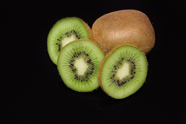 Whole and sliced Kiwi on black background