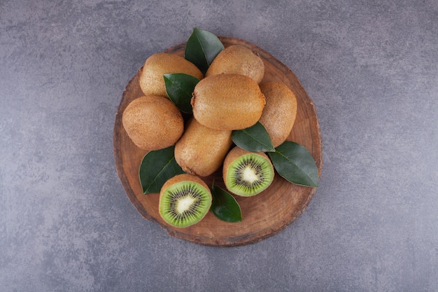 Whole and sliced kiwi fruits with leaves placed on a stone .