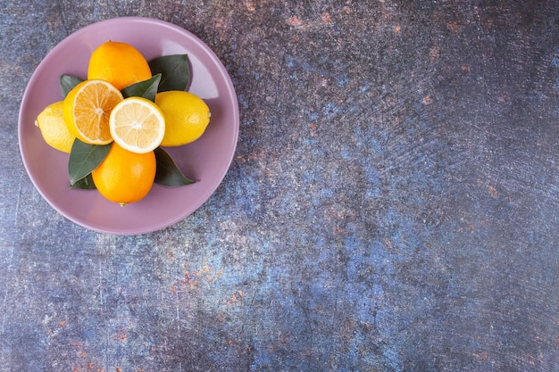 Whole and sliced lemon fruits placed on a stone .