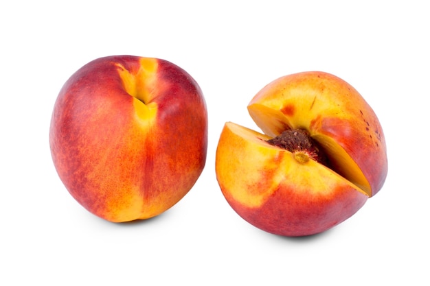 Whole and sliced nectarine opened to just reveal the pip inside standing side by side on a white background