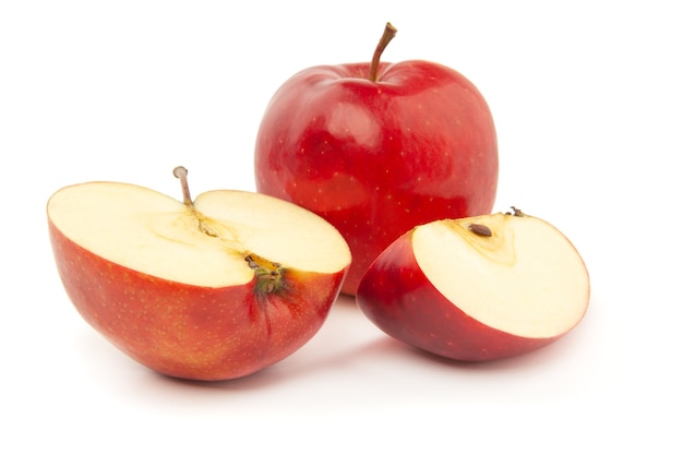 A whole and sliced red apple on a white surface