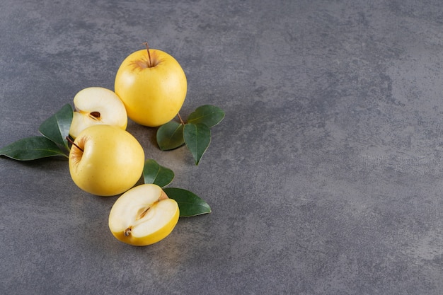 Whole and sliced yellow apple fruits placed on stone table . 