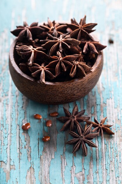 Whole star anise in a bowl on blue wooden background