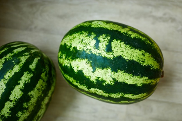 Whole stripe watermelons close up on white surface,  top view, summer time. Copy space.