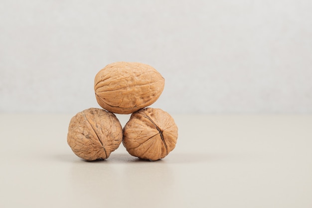 Whole three healthy walnuts placed on white.