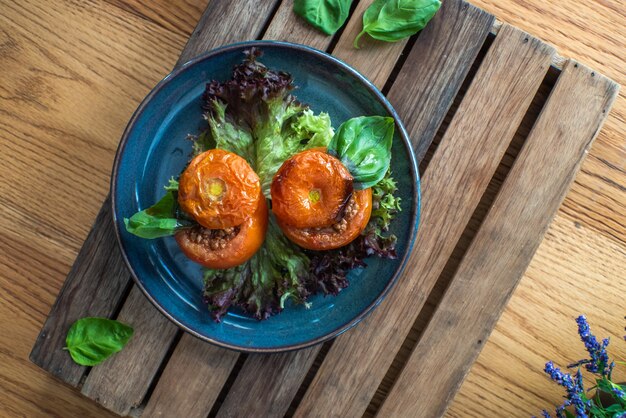 Whole tomato stuffed with ground beef chili on wooden table