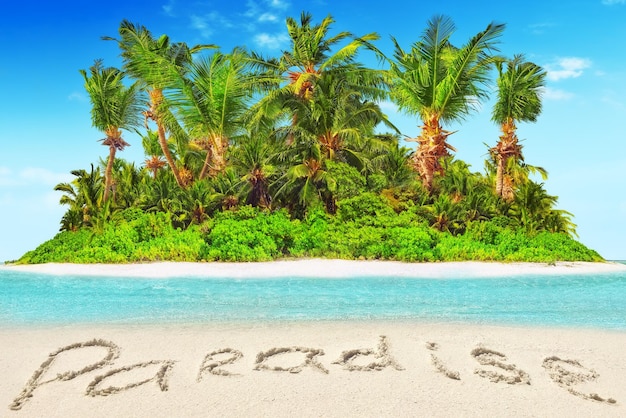 Foto intera isola tropicale all'interno dell'atollo nell'oceano tropicale e iscrizione paradiso nella sabbia su un'isola tropicale