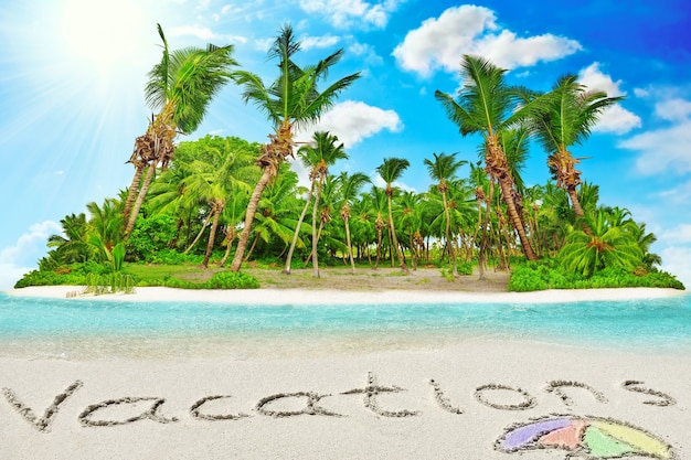 Whole tropical island within atoll in tropical Ocean. Uninhabited and wild subtropical isle with palm trees. Inscription "Vacations" in the sand on a tropical island,  Maldives.