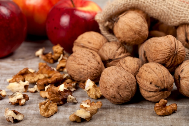 Whole walnuts, kernels and apples on the table