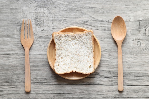 Whole wheat bread in the wooden bowl with spoon and fork on wooden background Healthy Eating and Diet concept