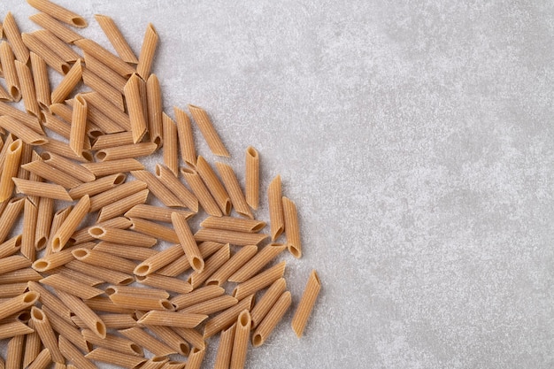 Whole wheat penne pasta over concrete countertop