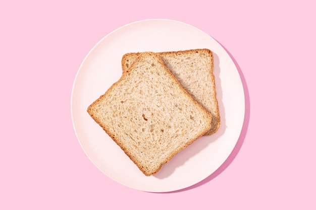 Whole wheat sandwich bread on plate on pink background Flat lay