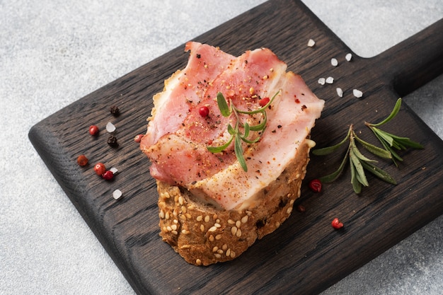 Wholegrain bread sandwiches with cream cheese, bacon on a wooden cutting Board.