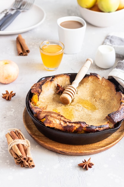 Photo wholegrain dutch baby pancake with apple, honey and spices (cinnamon and anise). delicious autumn or winter breakfast.