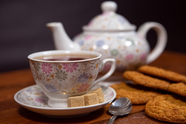 Цельнозерновое овсяное печенье с чашкой чая и сахаром на деревянном столе