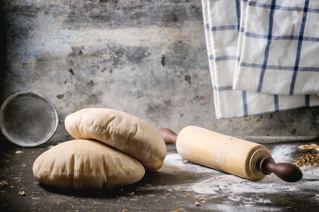 Photo wholegrain pita bread with rolling pin on table