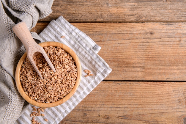 Wholegrain uncooked raw spelt farro in bowl on the wooden background