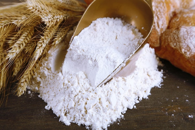 The wholemeal flour in scoop on wooden table