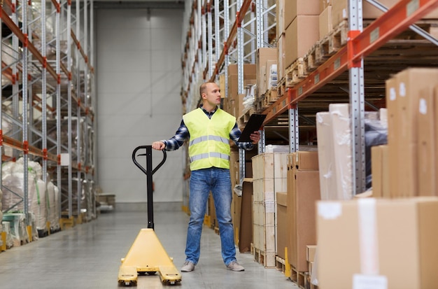 wholesale, logistic, loading, shipment and people concept - man with loader and clipboard at warehouse