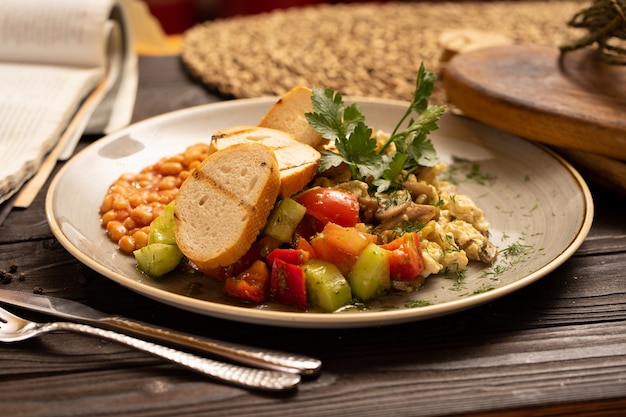 A wholesome healthy breakfast of omelet beans with mushrooms, vegetables, tomatoes, bell peppers, cucumbers, parsley and dill