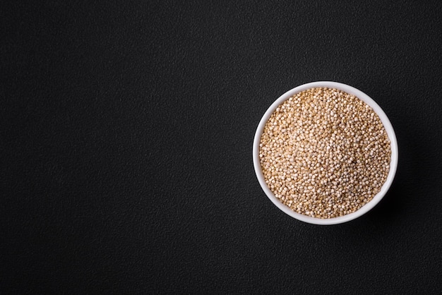 Wholesome raw quinoa in a bowl on a dark concrete background