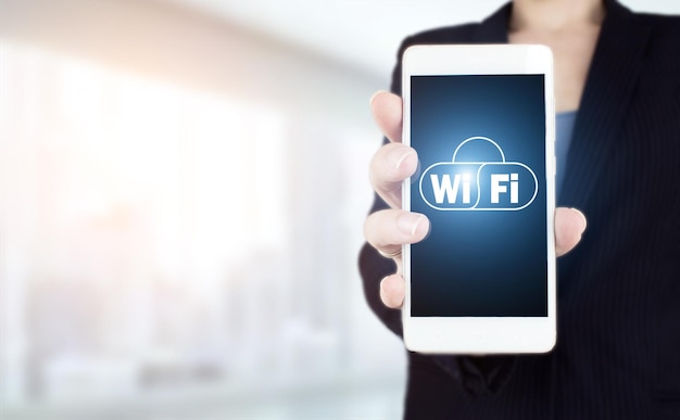 Wi-Fi draadloos concept. Hand houden witte smartphone met digitaal hologram Wi Fi teken op lichte onscherpe achtergrond. Gratis wifi-netwerksignaaltechnologie internetconcept.