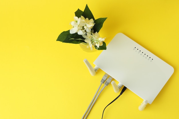 Wi-Fi router and flowers on yellow background